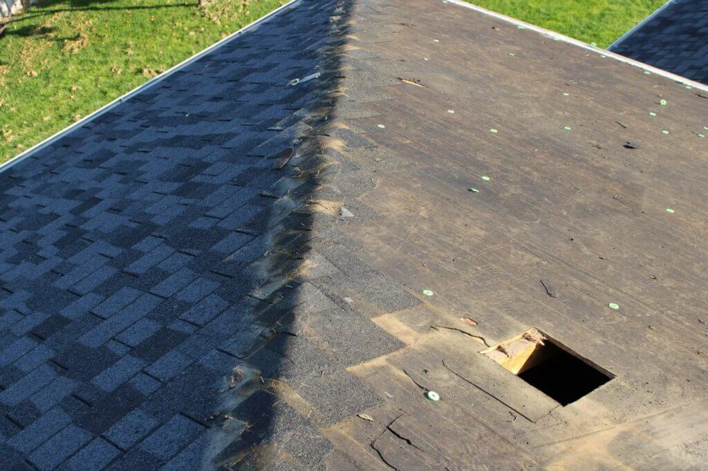 Top view of a partially replaced roof, showing new shingles on one side and exposed decking on the other.