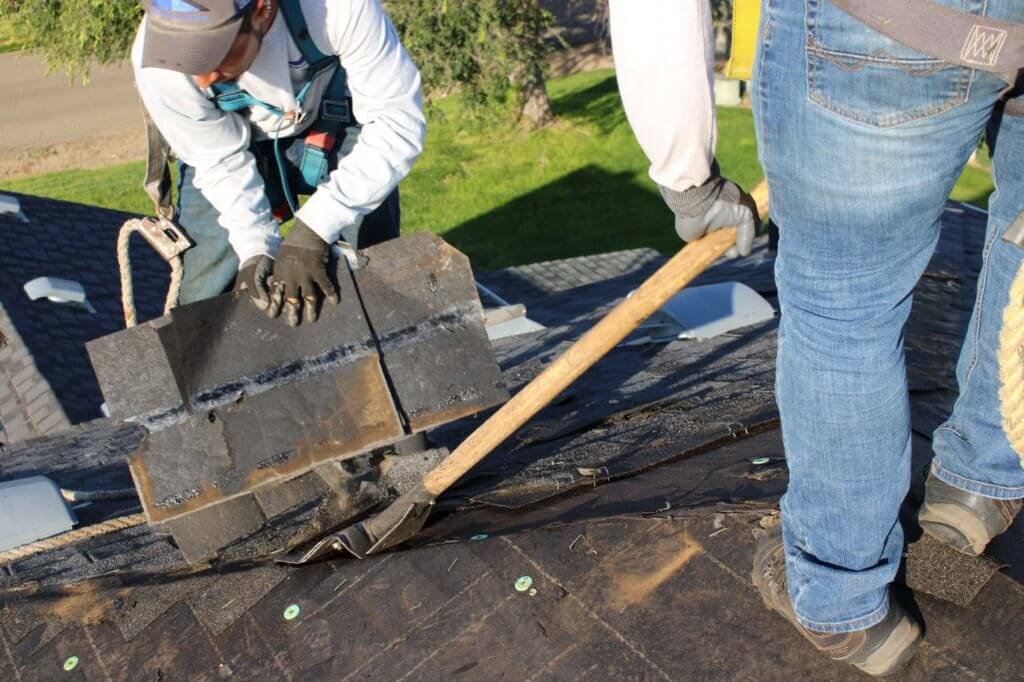 Roof Replacement team working on tearing up old roof parts to replace