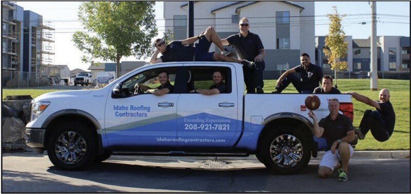Team members of Idaho Roofing Contractors posing on and around a company truck.