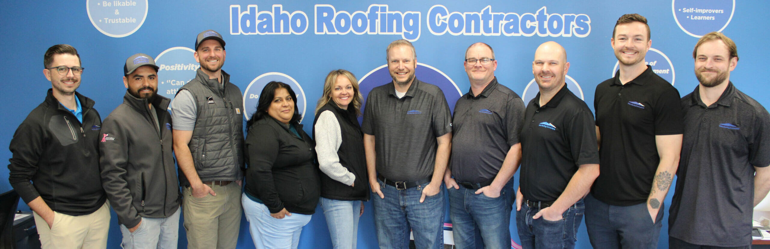 Group picture of the Idaho Roofing Contractors team standing in a row with dark shirts on.