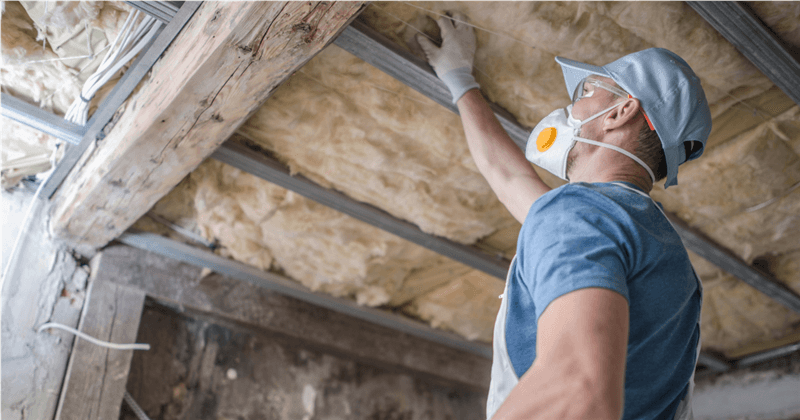 man in ppc gear inspecting insulation in an attic