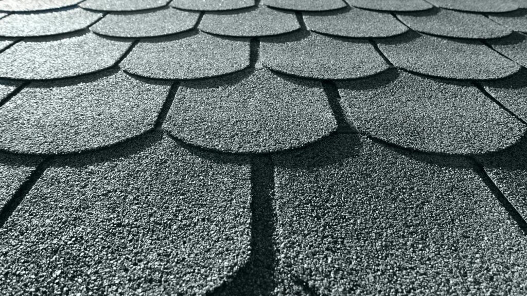 A close up view of asphalt roofing shingles on a home, gray. 