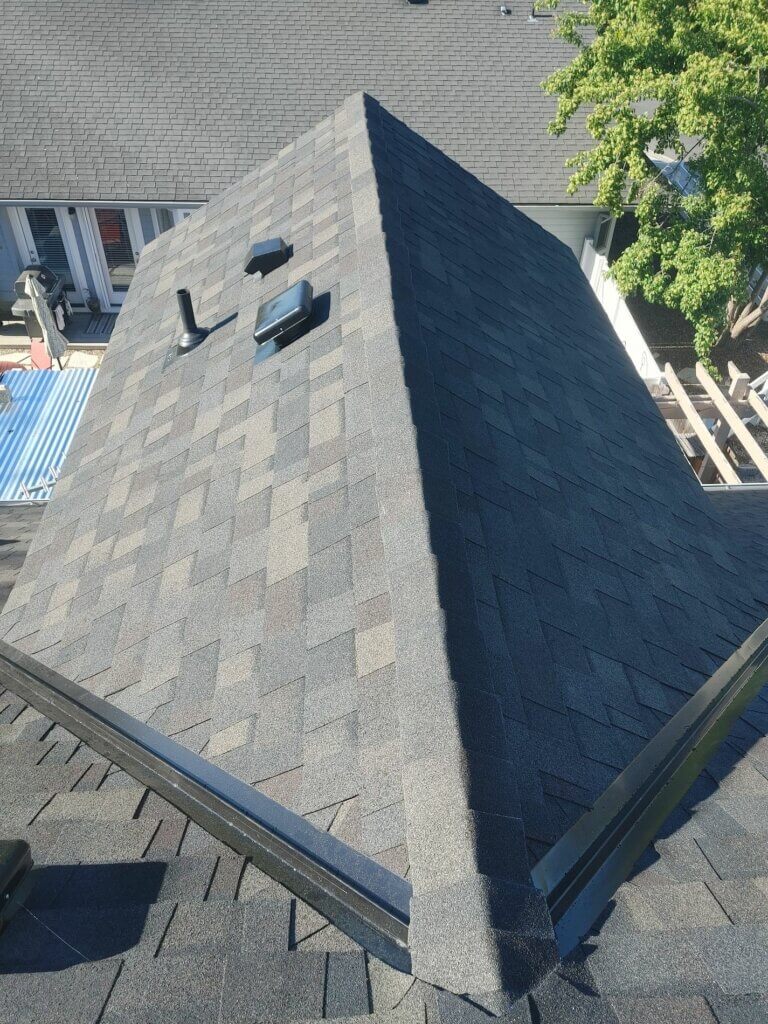 A newly installed shingle roof with vents and skylights, viewed from above.