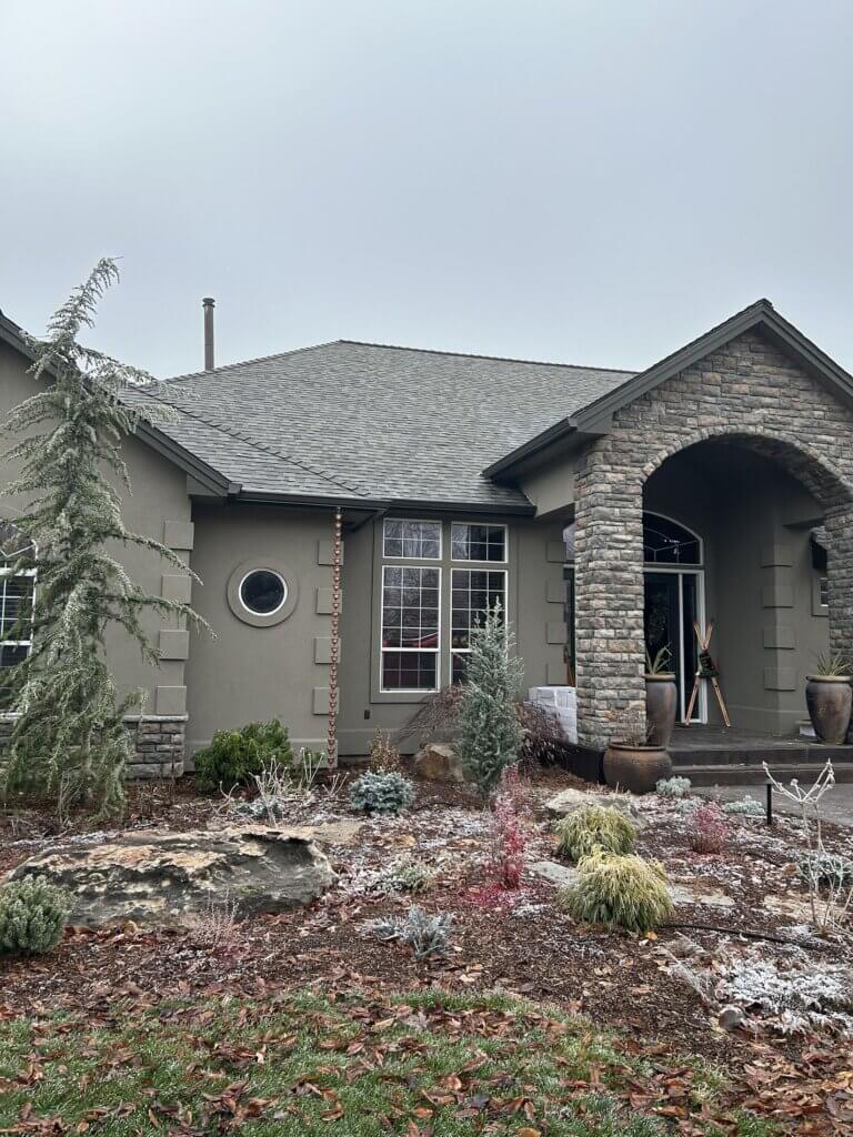 Upscale home with dimensional shingle roof, stone accents and stucco exterior in winter landscaping.