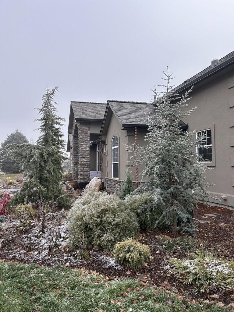 Custom home with architectural shingle roof, stone accents and stucco exterior in winter setting.
