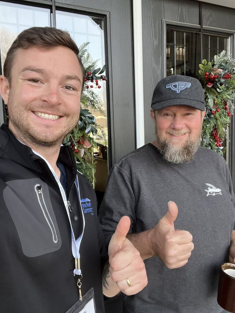 Roofing consultant and satisfied customer giving thumbs up at the doorway or a house.