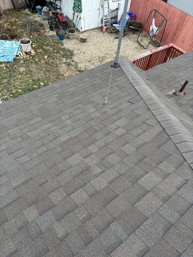 Gray shingle roof with ridge cap, electrical mast anchor, and plumbing vent pipe visible.