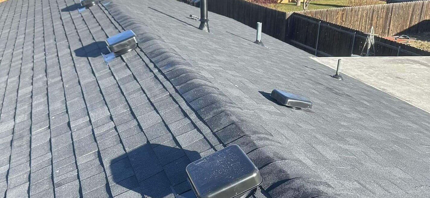 Multiple vent pipes, attic ventilation boxes, and a steep-pitch shingle roof with a consistent ridge detail.