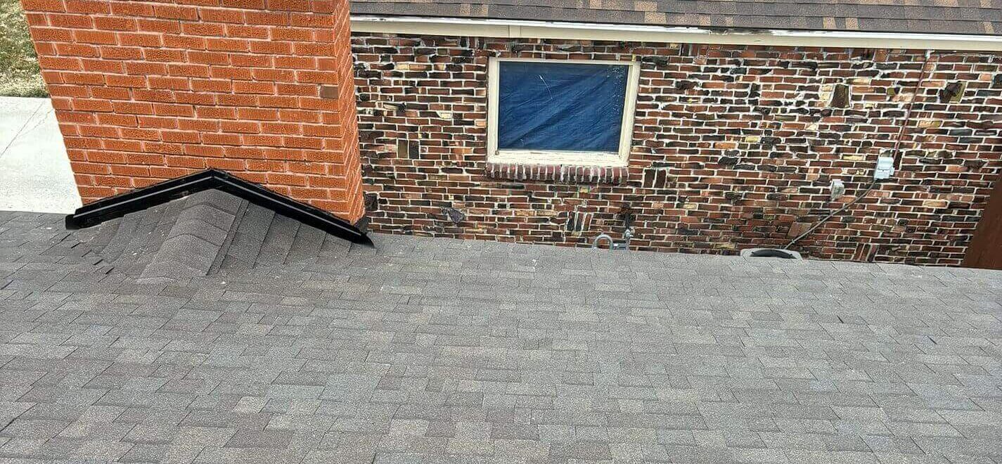 Rooftop view displaying details of the sealed chimney flashing, clean ridge transitions, and asphalt shingles.