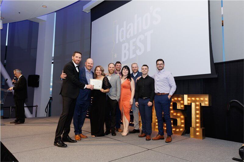 Team members accept an award on stage at the Idaho’s Best ceremony, posing with a certificate.