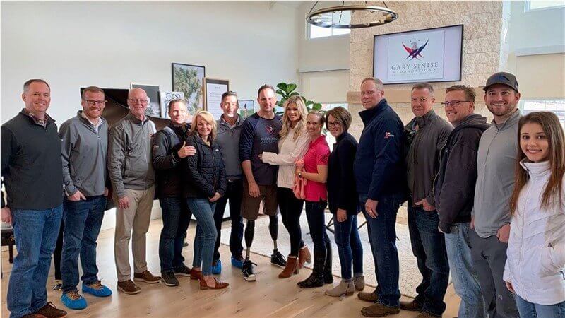 Team members, service members, and community supporters pose together at a Gary Sinise Foundation event.