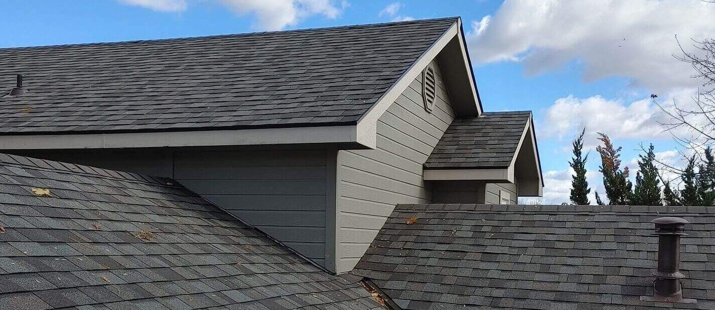 Close-up of metal valley flashing and laminated shingles demonstrating a waterproof connection between intricate slopes.