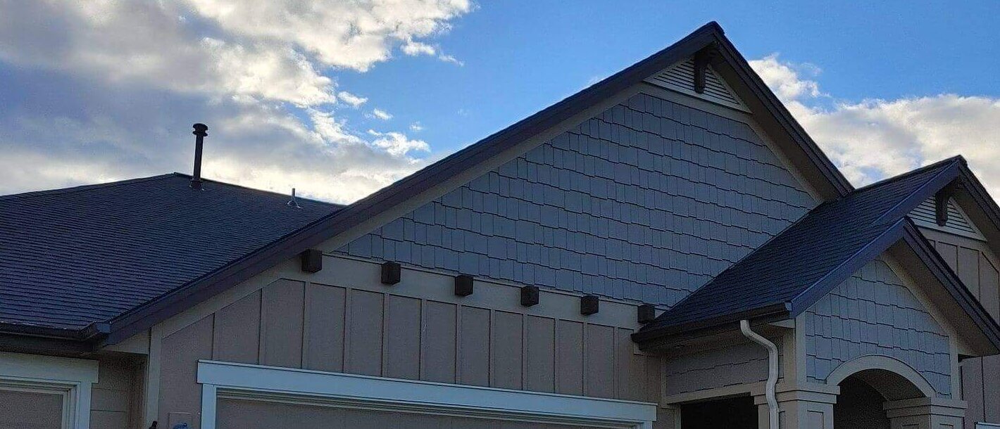 A craftsman-style home with a large driveway and shake siding has a recently installed roof with clean lines.