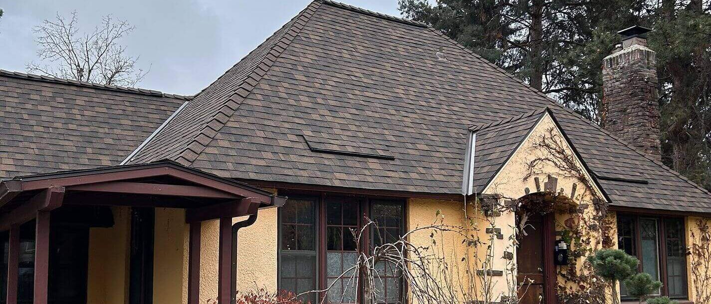 Tudor-style house with architectural shingles and matching vent covers on a high-pitch roof.