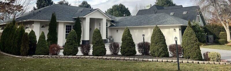 A multi-sectional home with front-facing gables and clean trim work has a dark gray shingle roof.