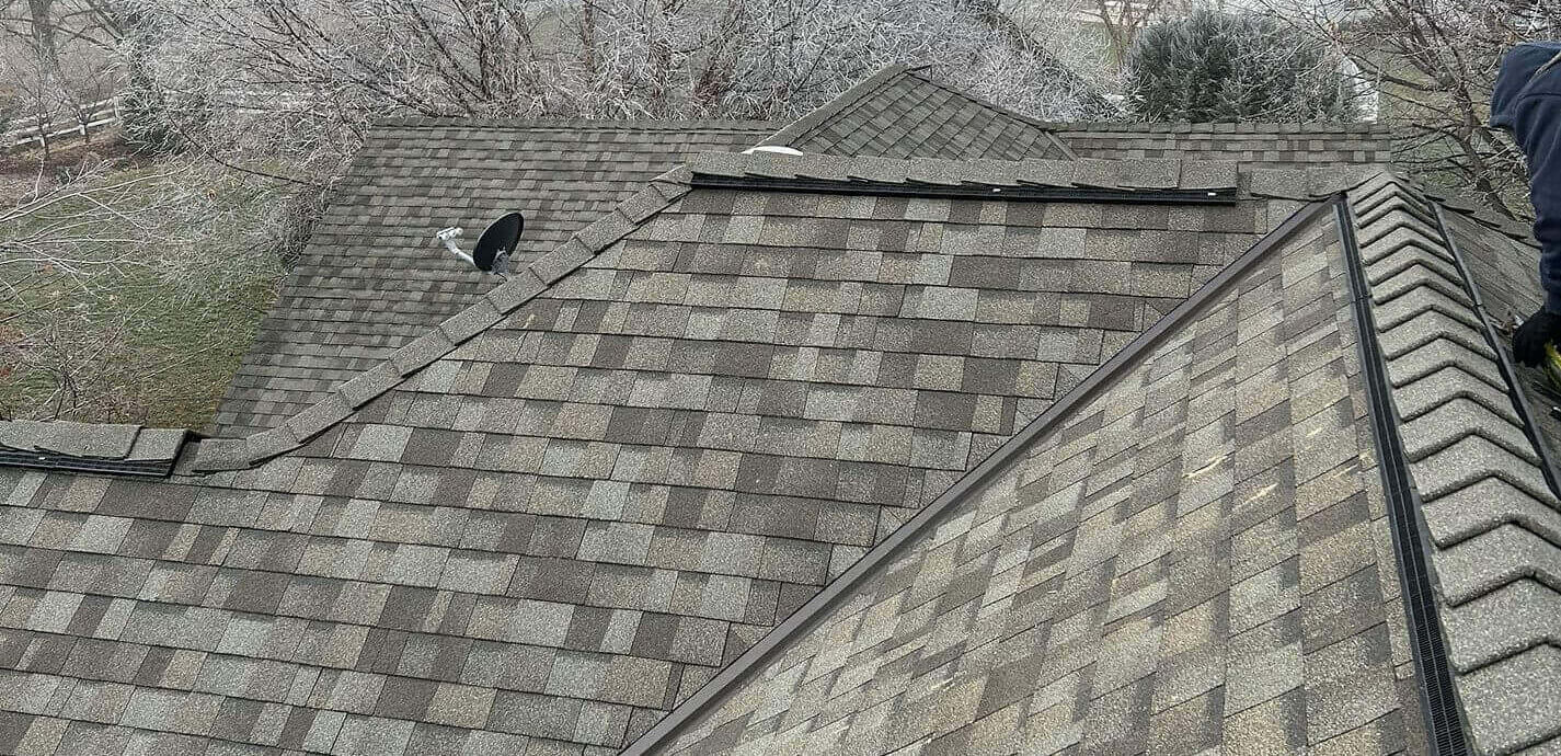 A gray architectural shingle roof with intersecting rooflines and sharp ridges.