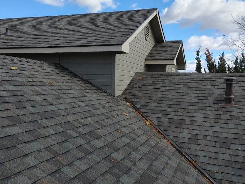 Roof valley with overlapping gray architectural shingles, showcasing precise installation on multi-level home.