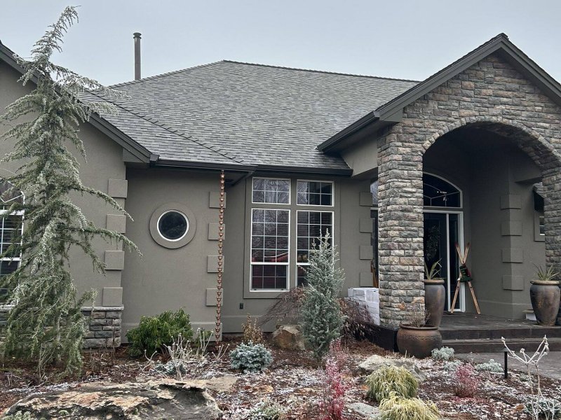 Upscale home with dimensional shingle roof, stone accents and stucco exterior in winter landscaping.