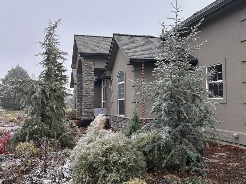 Custom home with architectural shingle roof, stone accents and stucco exterior in winter setting.