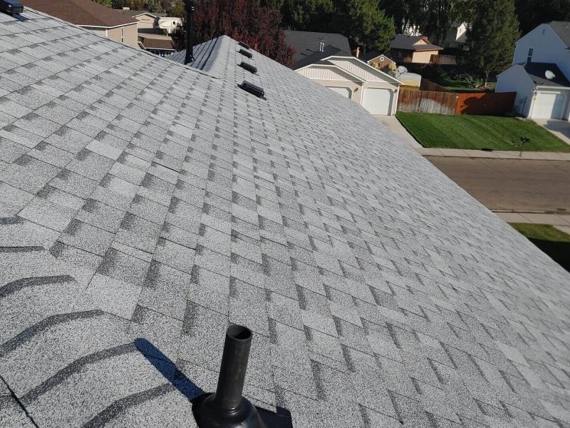 ray architectural shingles with pipe flashing, showcasing precise installation across steep residential roof slope.
